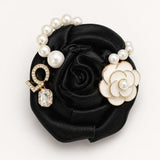 Broche flor preta de cetim com pérolas, pingente oval transparente e camélia dourada