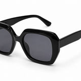 Óculos de sol com armação preta e lentes escuras, formato retrô