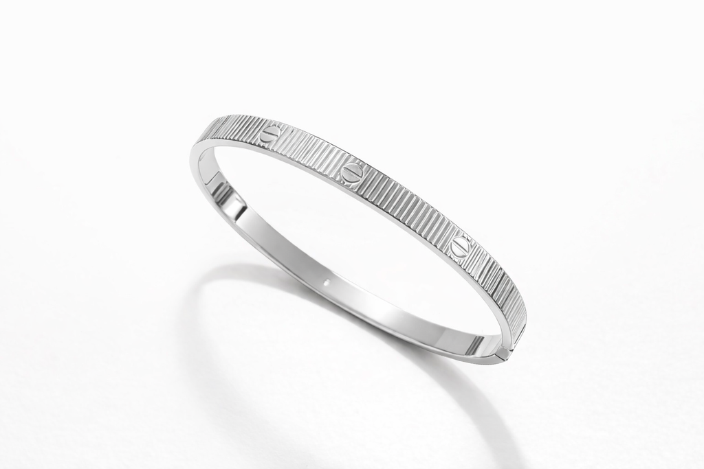 Pulseira Carti de listras prateadas, aro fino com padrão gravado e brilho metálico.