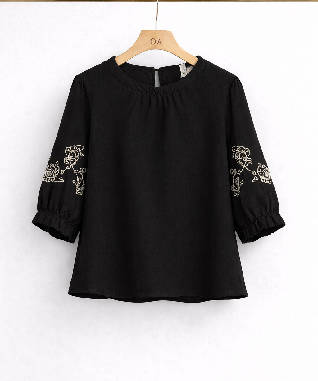Blusa preta com bordado branco nas mangas, gola franzida e punhos franzidos