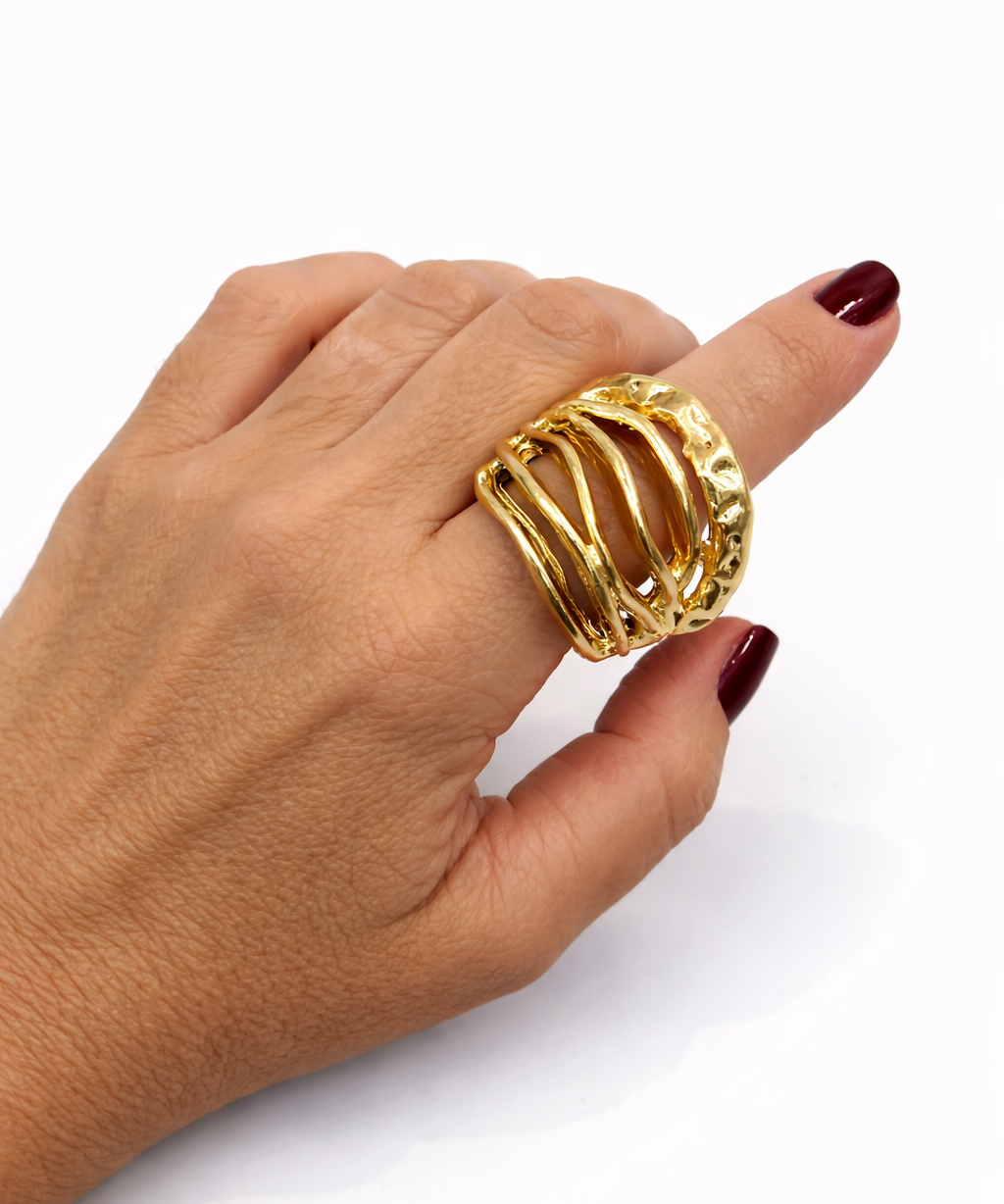 Anel dourado oval com faixas onduladas e textura trabalhada, no dedo