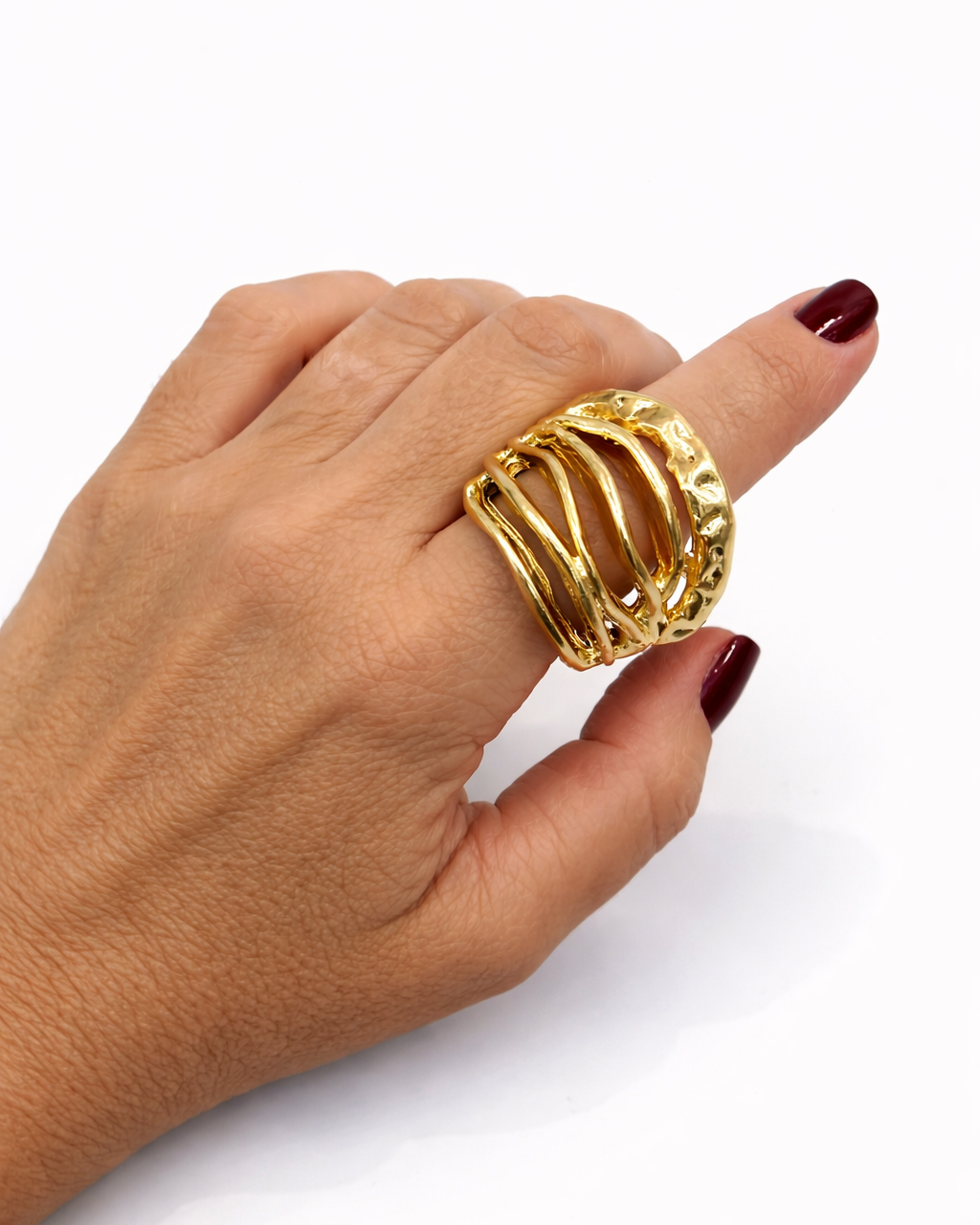 Anel dourado oval com faixas onduladas e textura trabalhada, no dedo