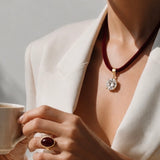 Colar com cordão marrom escuro e pingente redondo com zircônias, metal dourado