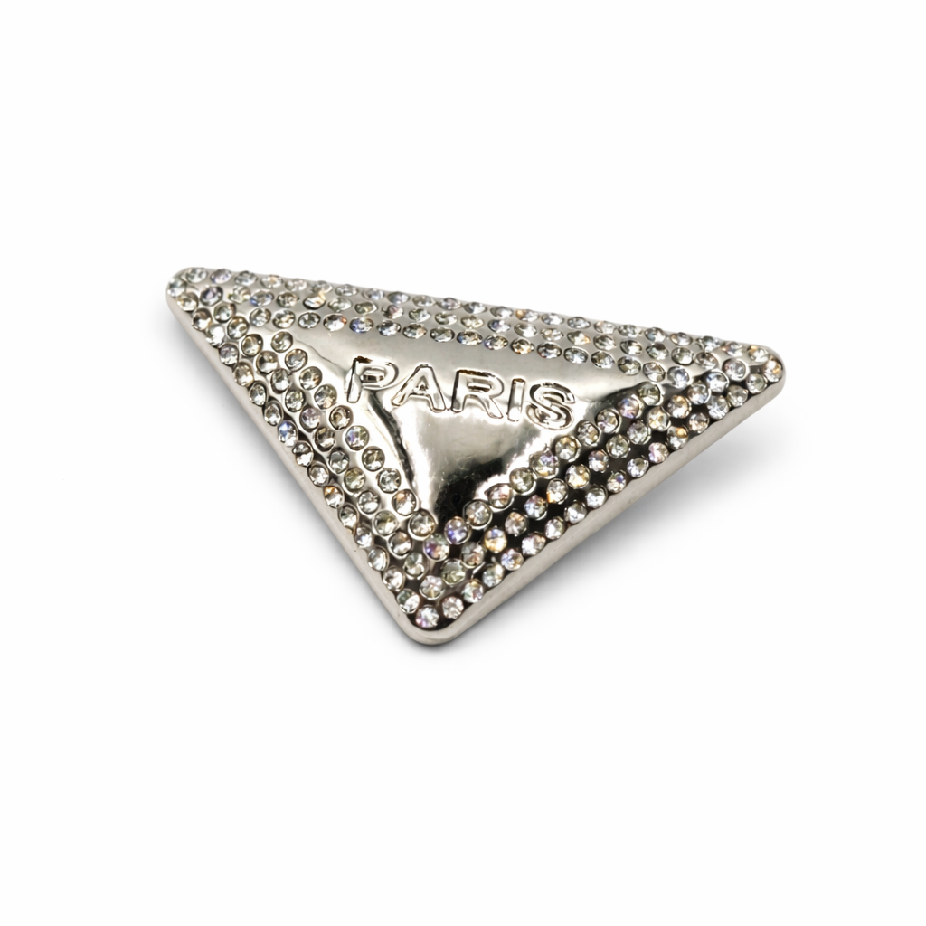 Broche triangular prateado com strass e escrita PARIS em metal