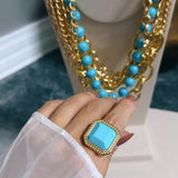 Anel Geneve azul com pedra quadrada azul em moldura dourada