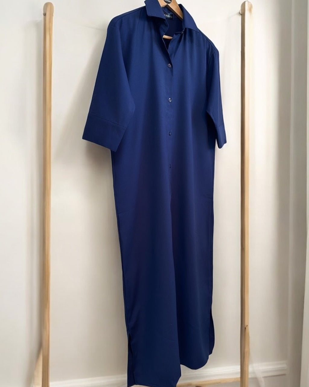 Camisa longa azul marinho, gola e botões, manga curta, barra reta com leve abertura lateral.