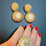 Anel dourado em formato de flor com textura radial e aro amplo