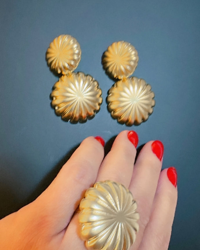 Anel dourado em formato de flor com textura radial e aro amplo