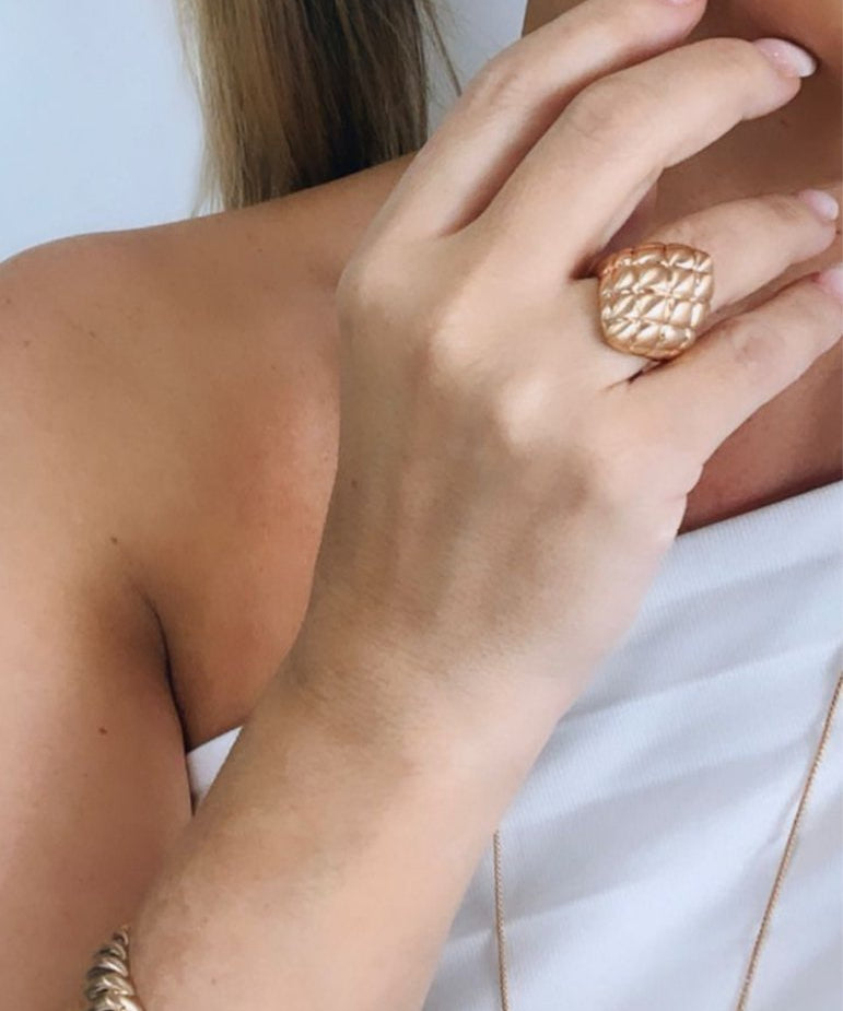 Anel Cloe dourado com textura trançada na parte superior, usado no dedo