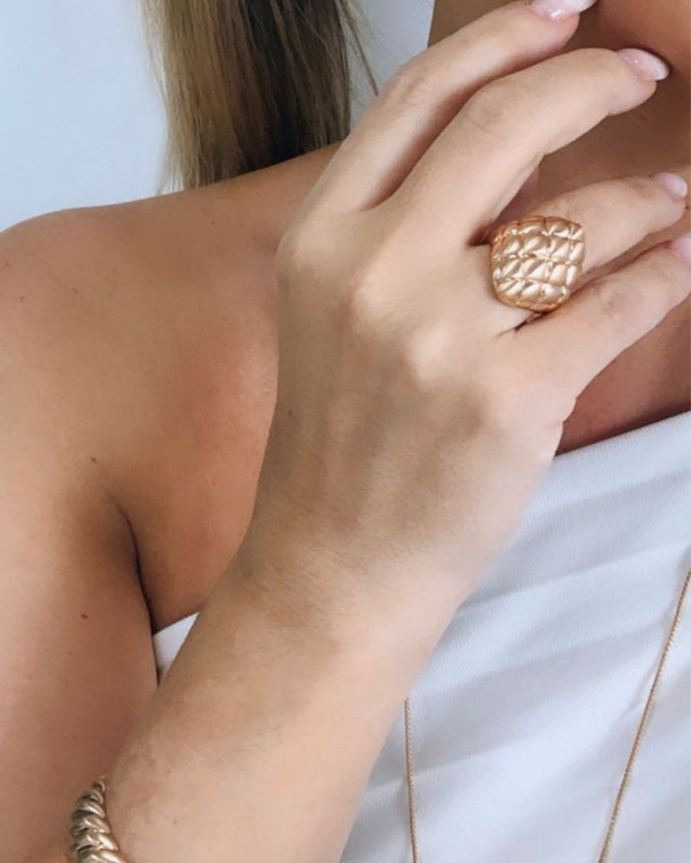 Anel Cloe dourado com textura trançada na parte superior, usado no dedo