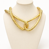 Colar de metal dourado com elos torcidos e pingente circular na interseção
