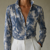 Camisa floral de manga longa azul e branca, gola aberta e botões frontais