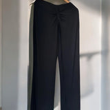 Calça pantalona preta com pregas no cós e pernas largas, vista traseira.