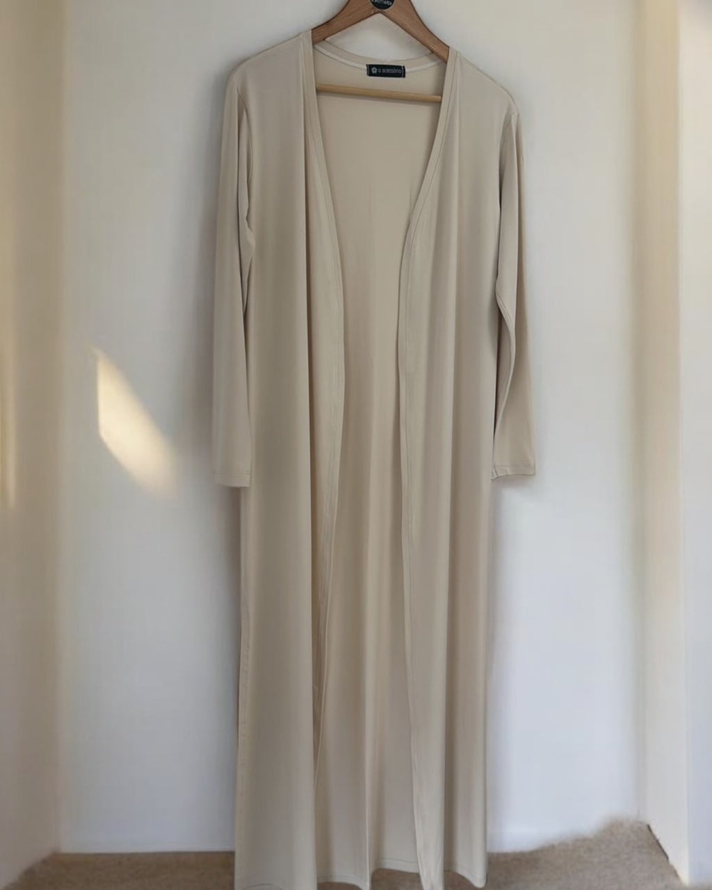 Cardigan longo bege com decote em V e mangas 3/4, caimento solto e aberto.