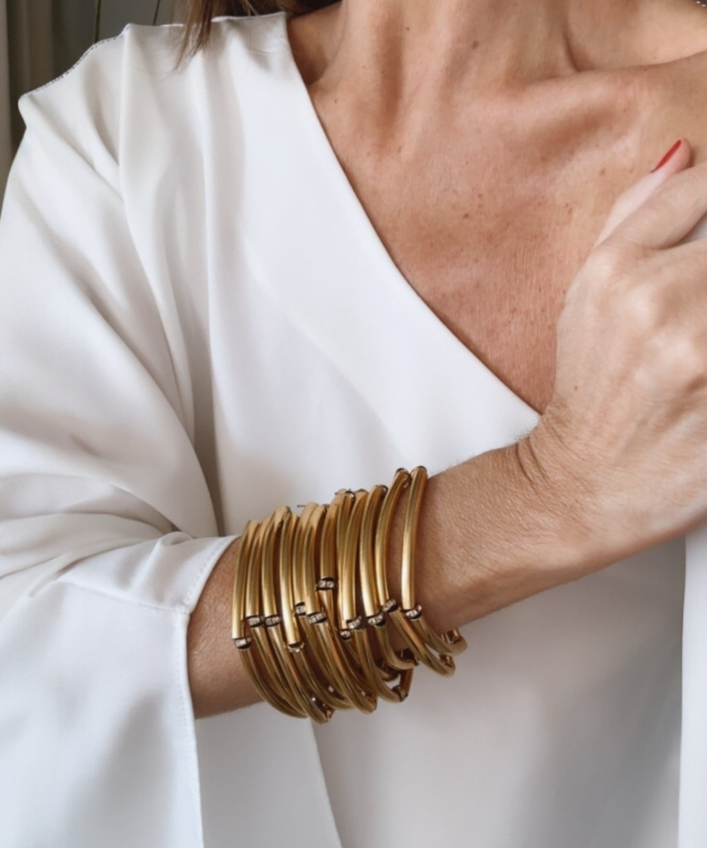 Pulseira dourada de braceletes múltiplos, com detalhes em tiras e elos