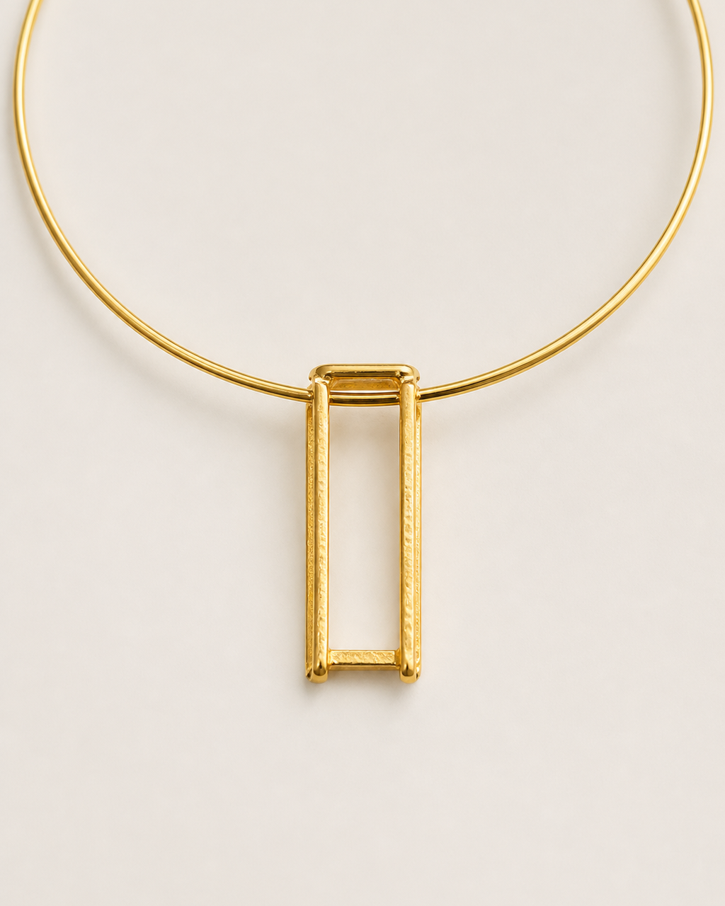 Detalhe do colar dourado com corrente e pingente retangular vazado