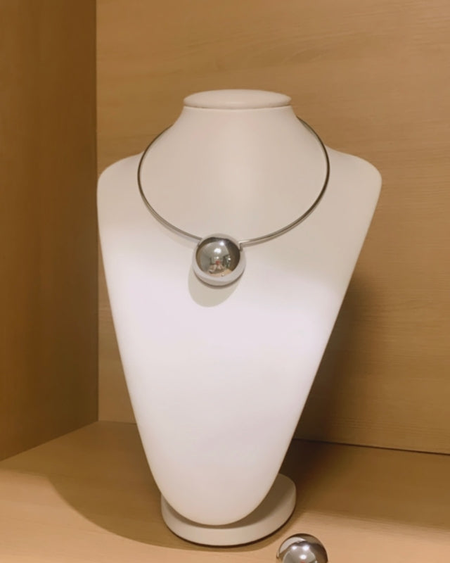 Colar prateado com pingente circular e esfera refletiva