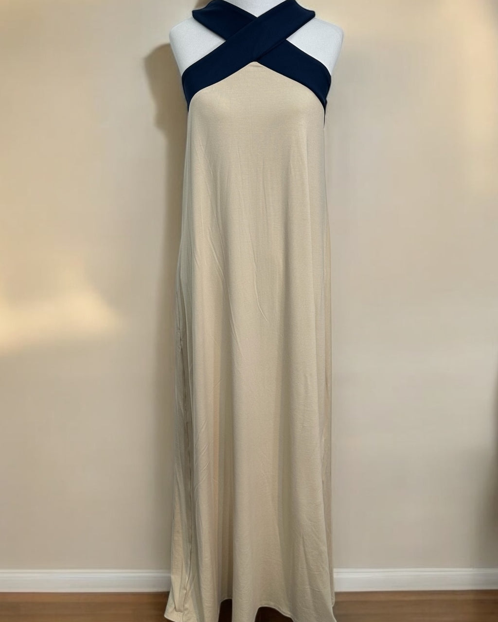 Vestido longo areia em manequim, com faixa cruzada azul-marinho no colo