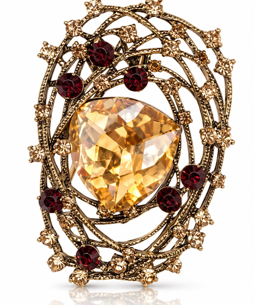 Broche metal dourado com pedra oval amarela e cristais vermelhos ao redor
