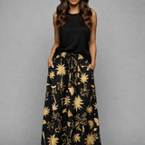 Saia longa preta estampada com flores douradas e claras, cós franzido e elástico