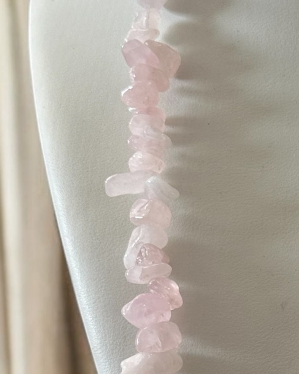 Pulseira de quartzo rosa com contas irregulares e fecho dourado em corrente.