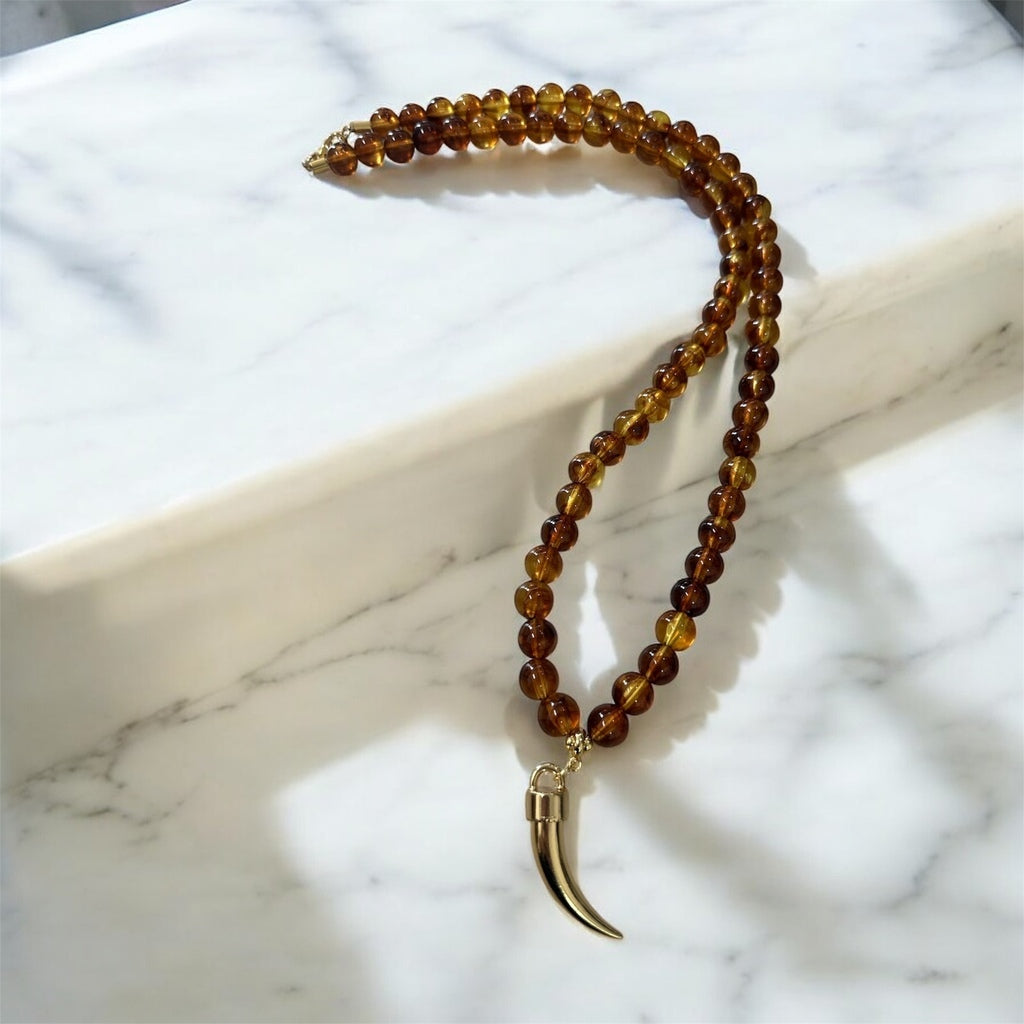 Colar de contas marrom com pingente de chifre dourado e fecho metálico