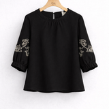 Blusa preta de gola franzida e bordado branco nas mangas bufantes, vista frontal