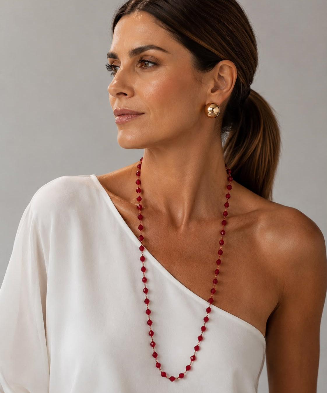 Colar Ana Julia de cristais vermelhos, usado em ombro com vestido branco