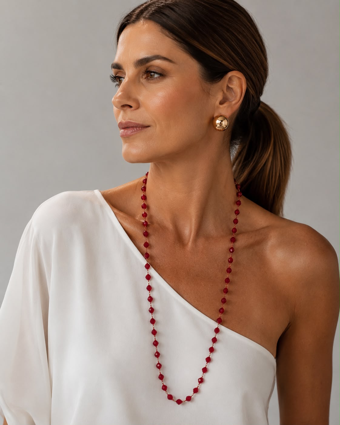 Colar Ana Julia de cristais vermelhos, usado em ombro com vestido branco