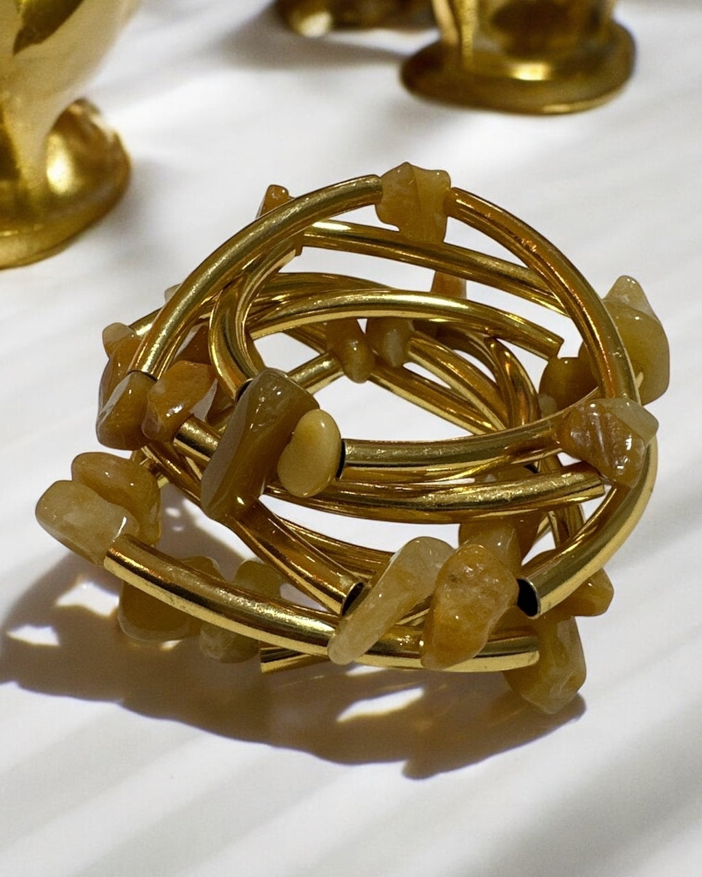 Pulseira dourada com pedras âmbar translúcidas e hastes trançadas