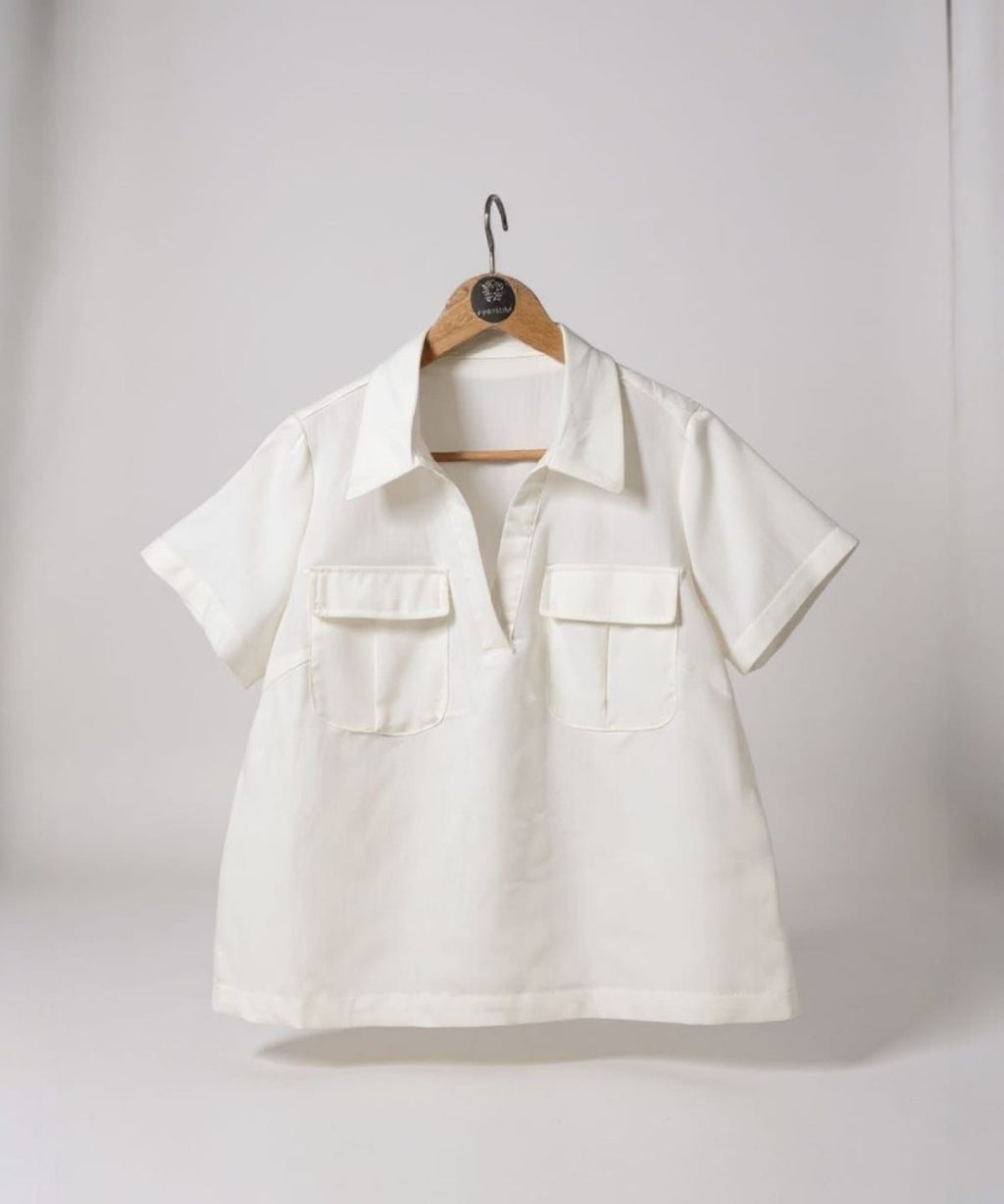 Blusa branca em cabide, gola polo, botões frontais e mangas curtas com bolsos