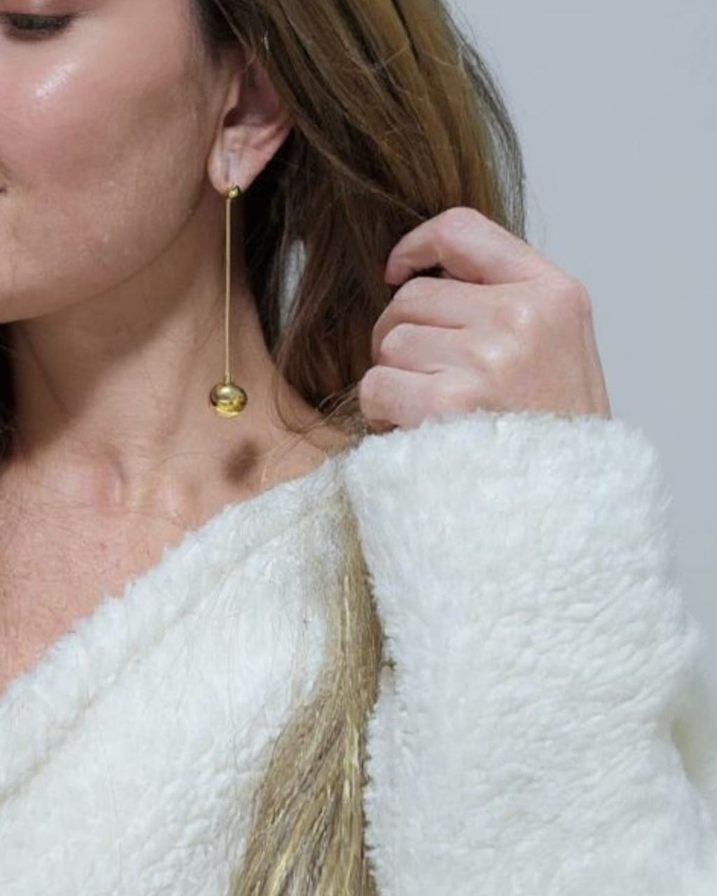 Brinco longo de esfera com haste fina e banho dourado, pendente no lóbulo da orelha
