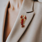 Broche de lagosta com cristais vermelhos e detalhes pretos em base dourada