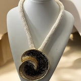 Colar Ocara com cordão trançado branco e pingente circular dourado com textura escura