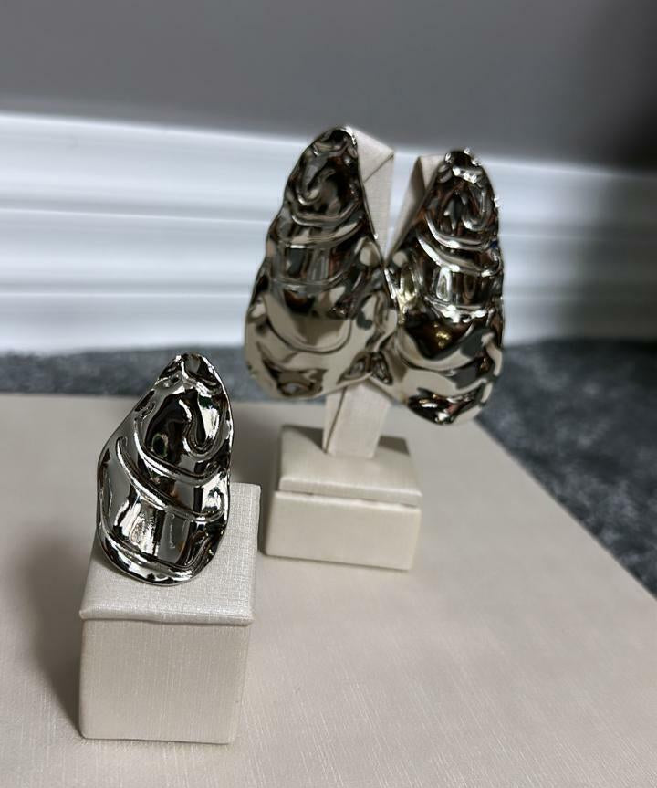 Par de anéis prateados com topo ornamentado e detalhe vazado