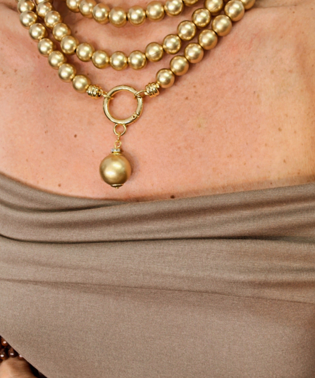 Colar de pérolas douradas com pingente sino dourado e aro circular