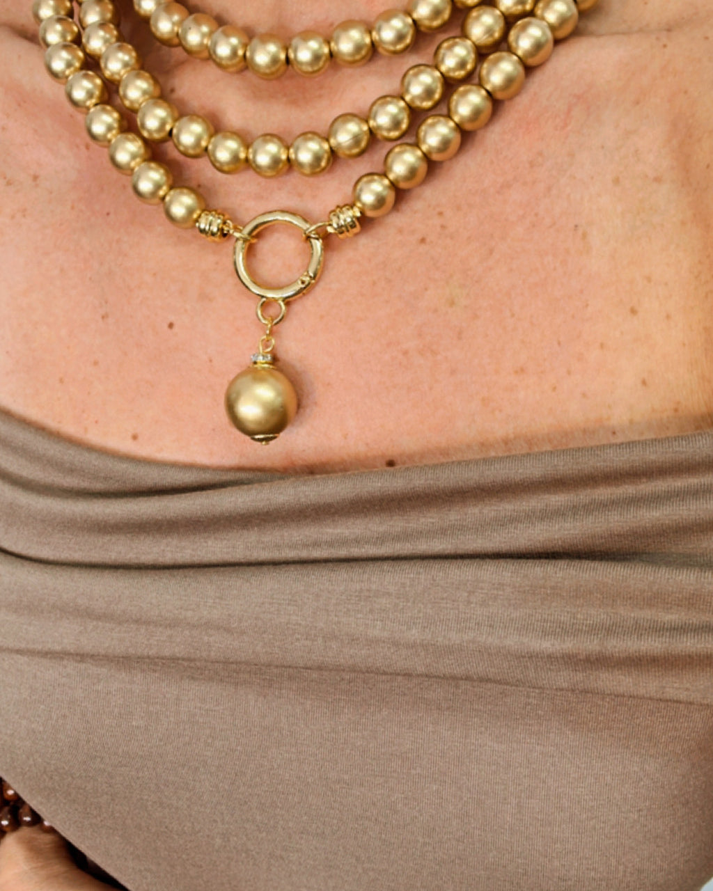 Colar de pérolas douradas com pingente sino dourado e aro circular