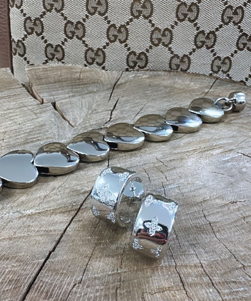 Brincos prateados com pingentes em formato de coração e detalhe brilhante