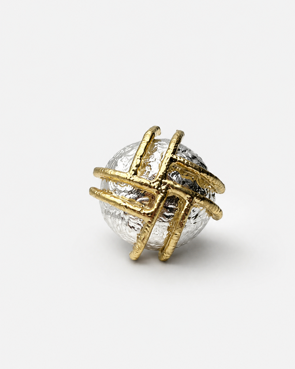 Anel oval dourado e prateado com faixa decorativa e pedra escura no centro