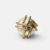 Anel oval dourado e prateado com faixa decorativa e pedra escura no centro
