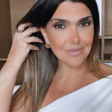 Brinco dourado Lia com aro e esfera texturizada, usado na orelha