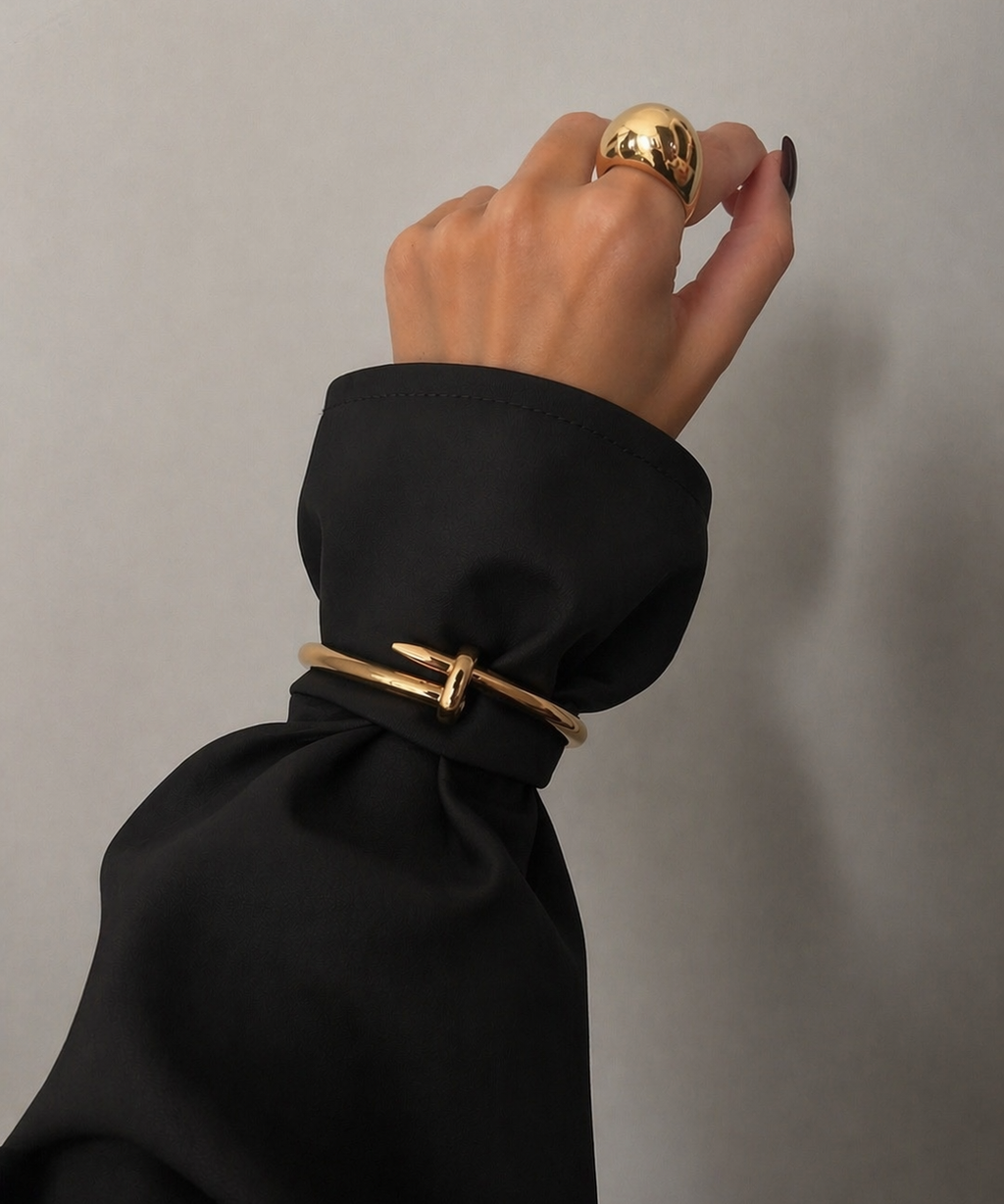 Pulseira dourada com fecho em formato de prego e detalhe central