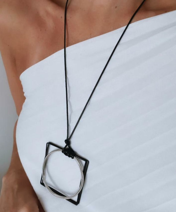 Colar de cordão preto com pingente prateado e detalhe preto em aro