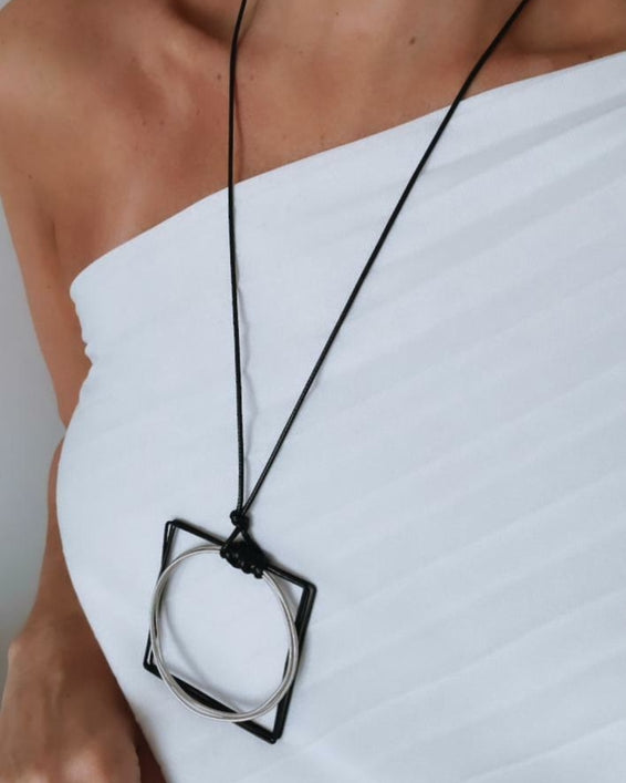 Colar de cordão preto com pingente prateado e detalhe preto em aro