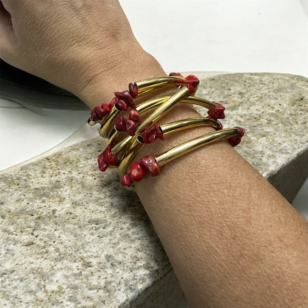 Pulseira folheada dourada com pedras vermelhas tipo grânulos no pulso