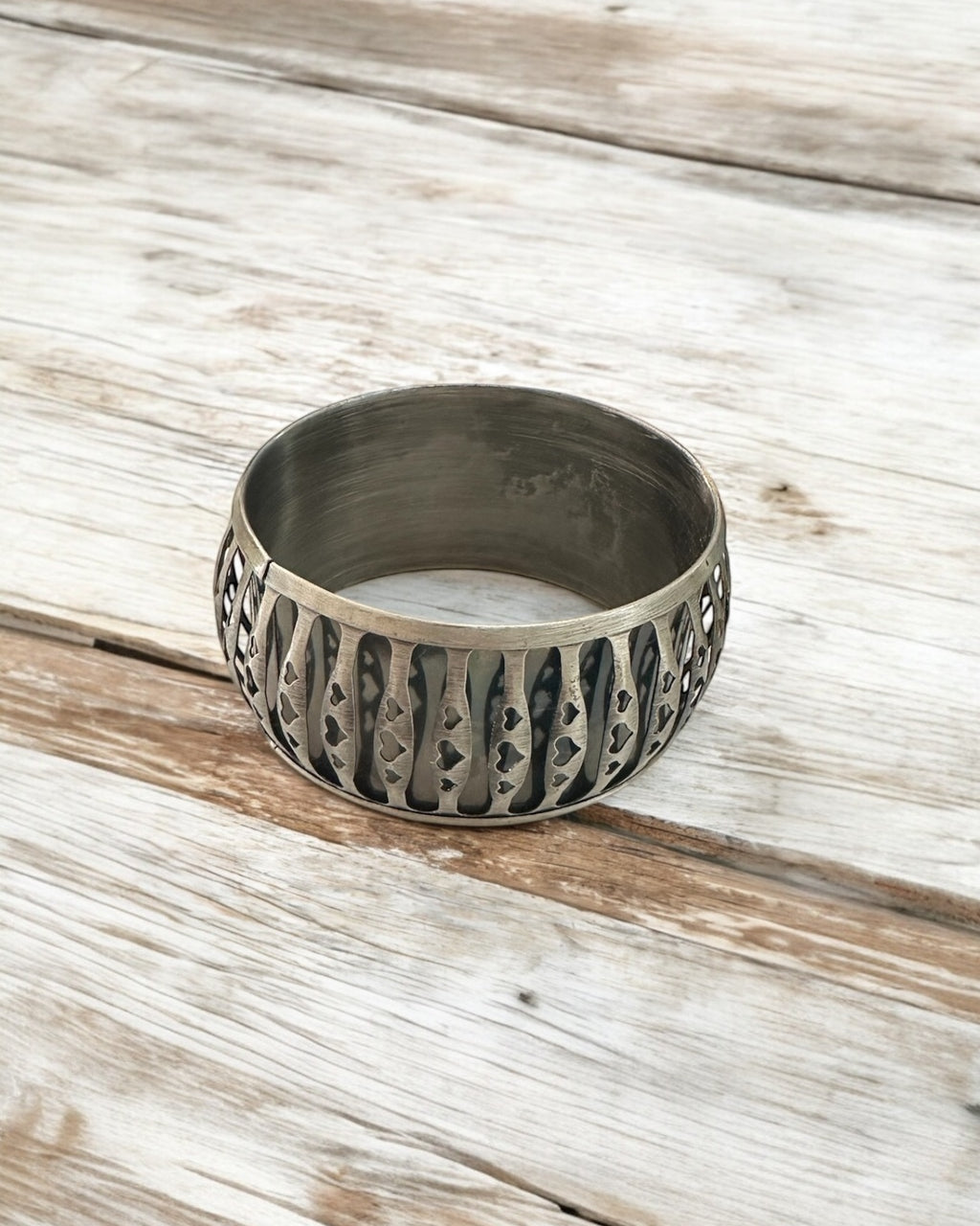 Bracelete metálico largo escuro com textura gravada e padrão decorativo