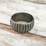 Bracelete metálico largo escuro com textura gravada e padrão decorativo