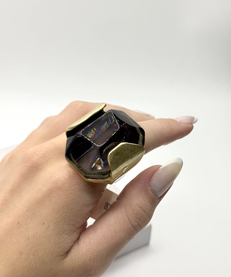 Anel com pedra escura e aro dourado quadrado com brilho multicolor