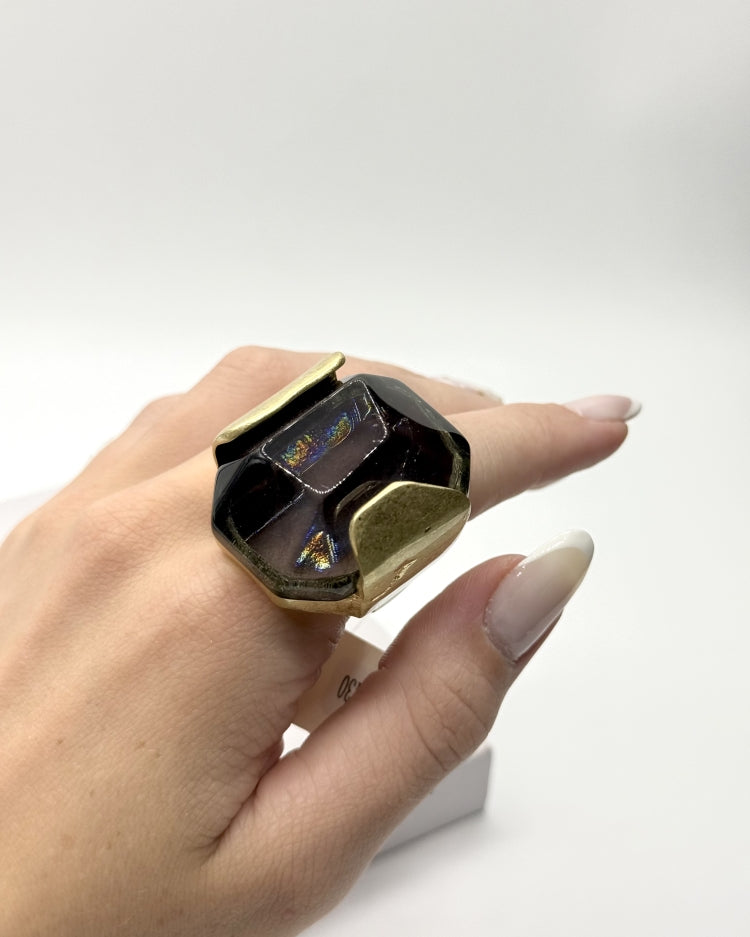 Anel com pedra escura e aro dourado quadrado com brilho multicolor