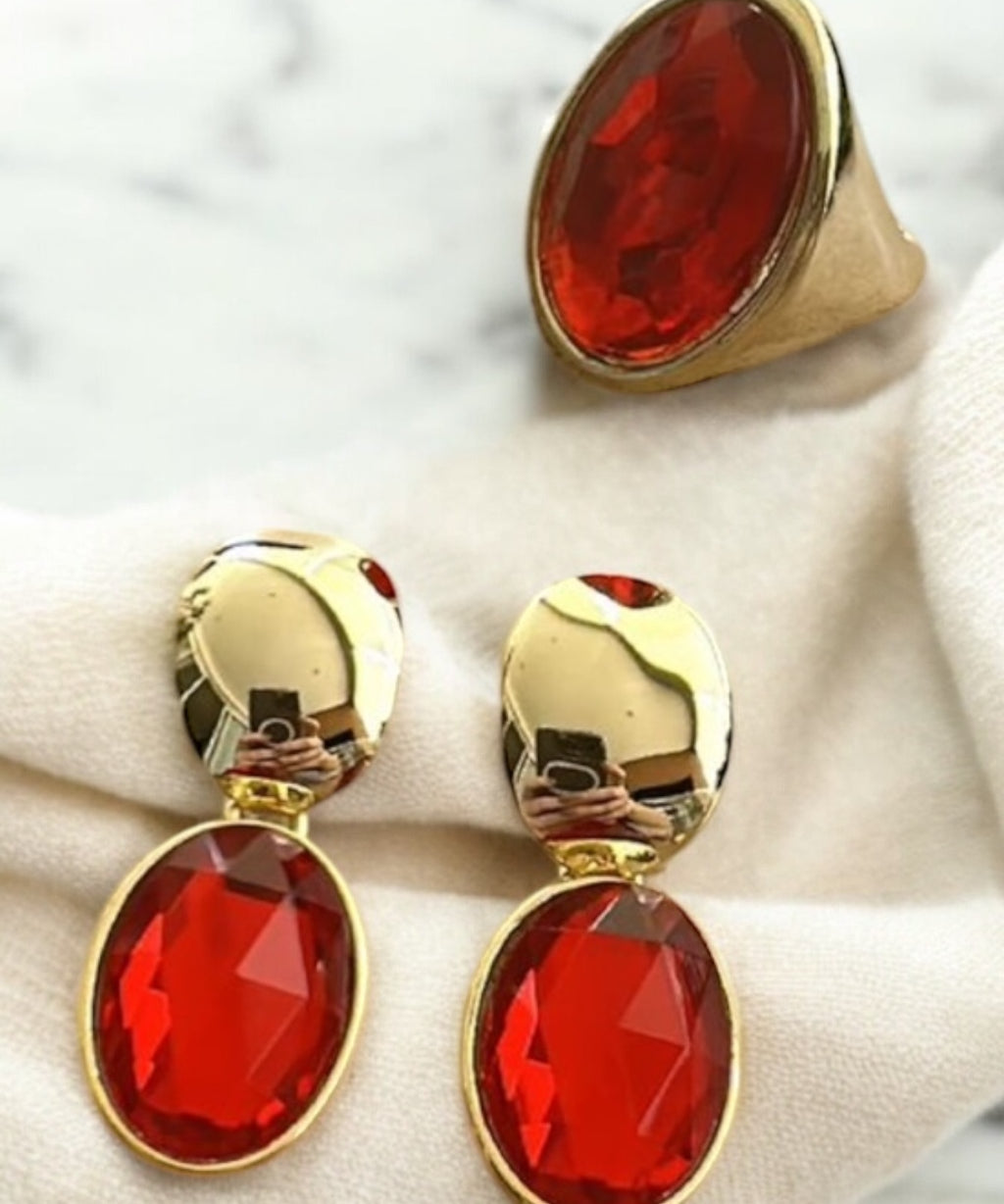 Anel Viena dourado com pedra oval vermelha em aro alto e borda dourada.